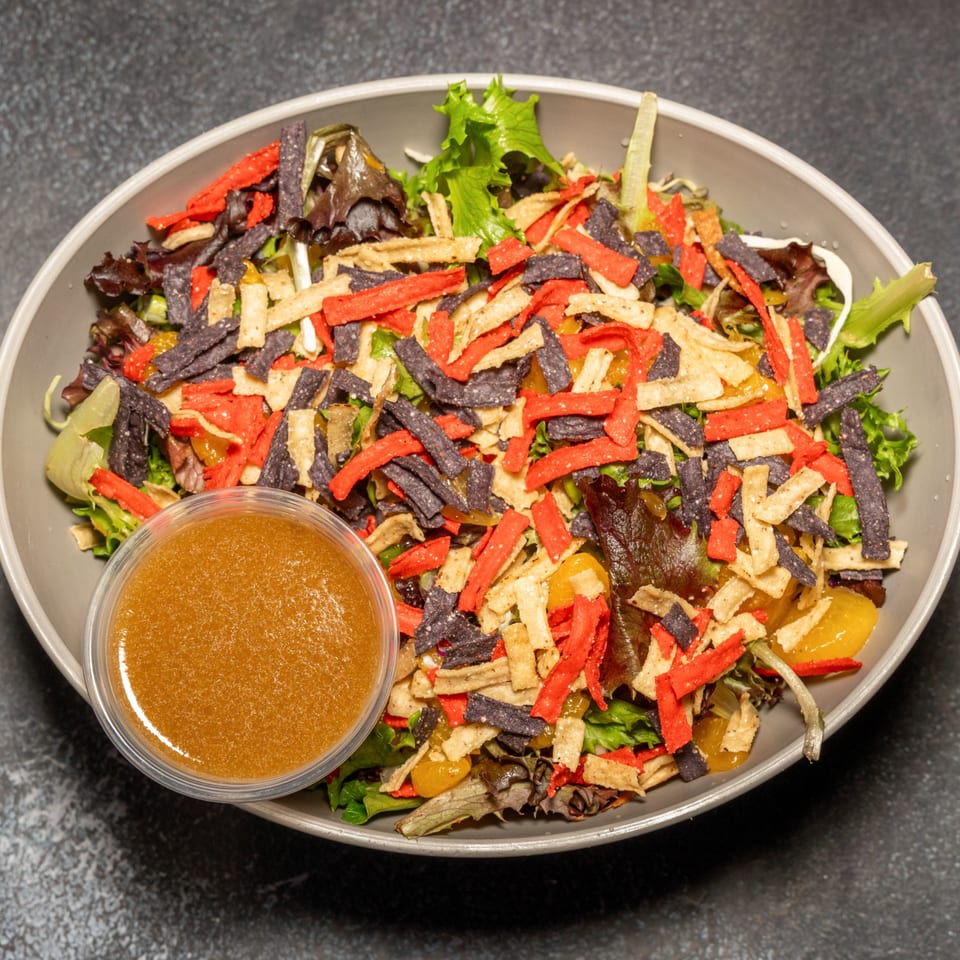 Cali's Sports Bar & Kitchen's colorful salad with mixed greens, tortilla strips, and dressing on the side.