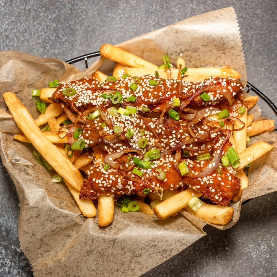 Cali's Sports Bar & Kitchen's fries topped with sweet chili chicken, sesame seeds, and green onions.