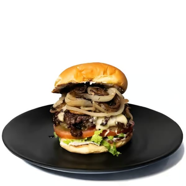 A Cali's Sports Bar & Kitchen burger with caramelized onions, lettuce, tomato, and cheese on a black plate.